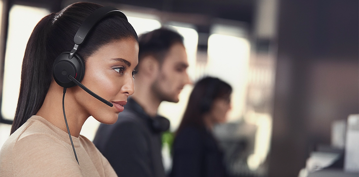 Typische Arbeitssituation im Callcenter, eine Frau mit Jabra Headsets im Vordergrund
