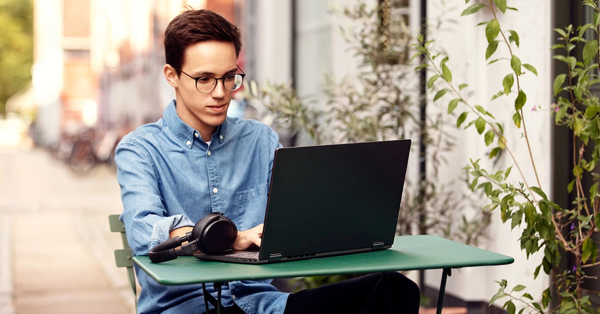 Ein Mann sitzt mit Laptop und Headset am Arbeitsplatz