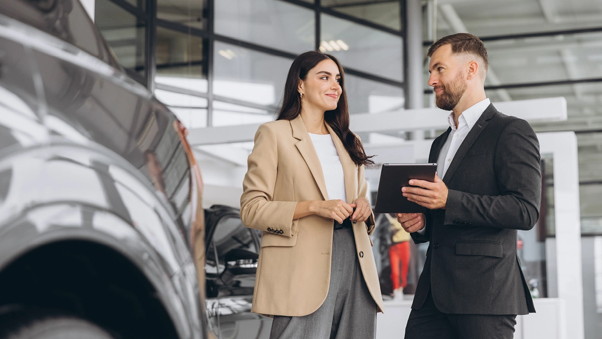Autohändler berät Kundin zu neuen PKW