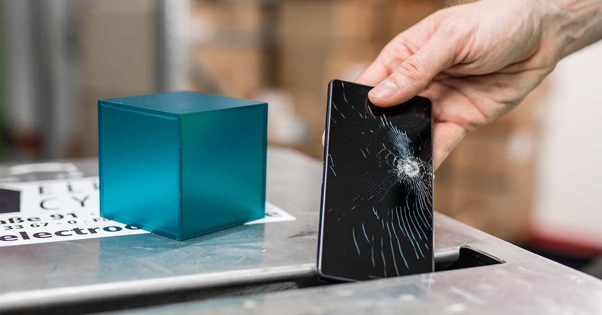 Kaputtes Smartphone wird in Recycling Box gelegt tuerkisfarbener Wuerfel auf Box